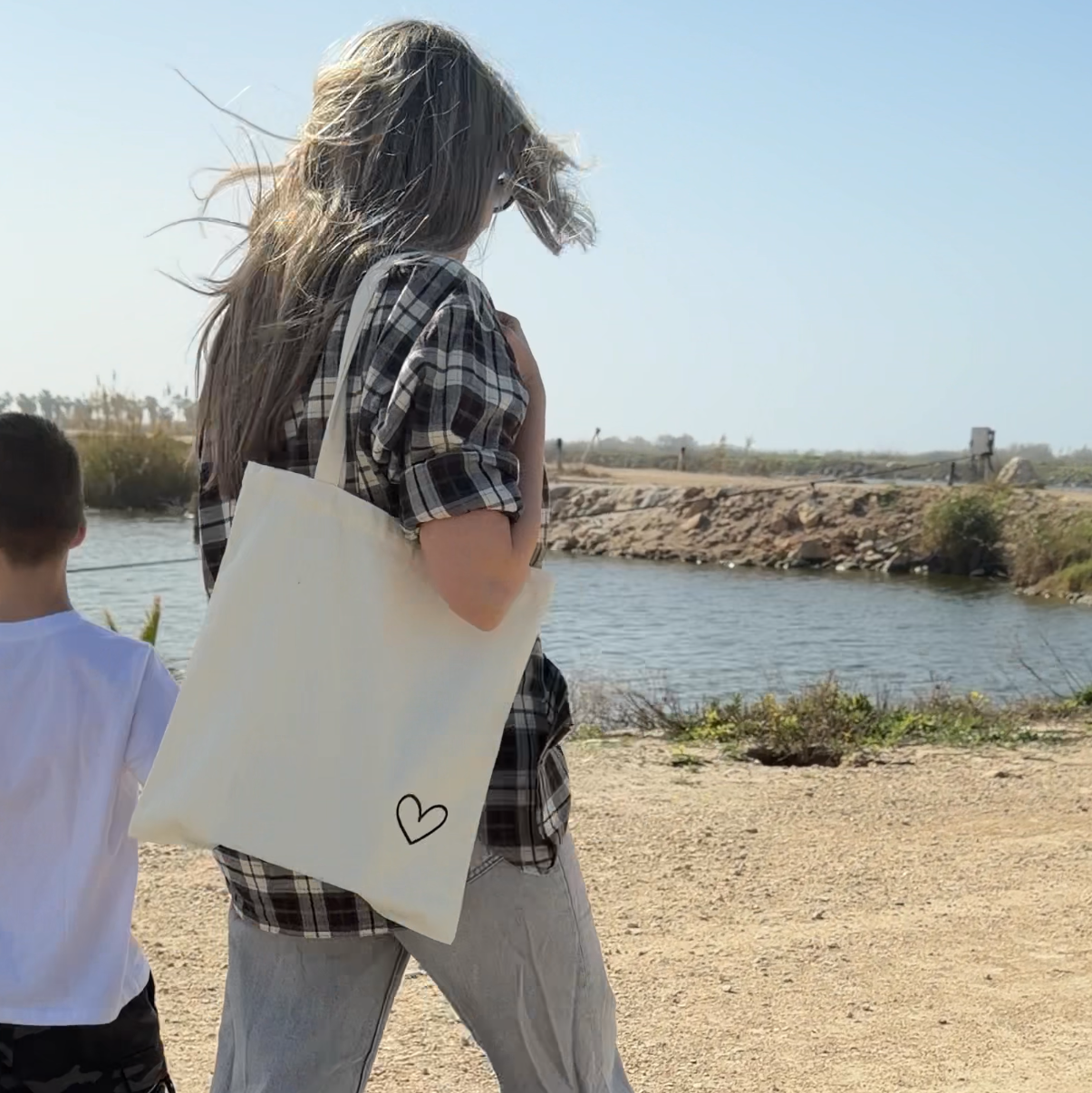 אישה הולכת בנוף טבעי עם תיק צד עם הדפס לב